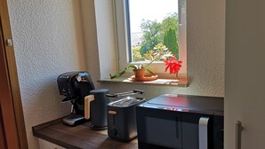 A kitchen with a coffee maker, toaster, and microwave on a wooden countertop. - Vacation apartment Hermann (Bovenden)