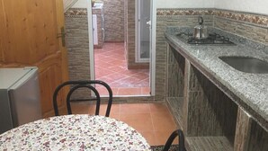 Una cucina compatta con fornelli a gas, un lavello e un'area pranzo con tavolo e sedie.