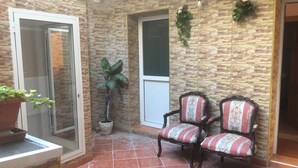 Una stanza con parete in mattoni, due sedie, una pianta in vaso e una porta.