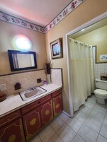 A bathroom with a sink, mirror, toilet, and shower curtain.