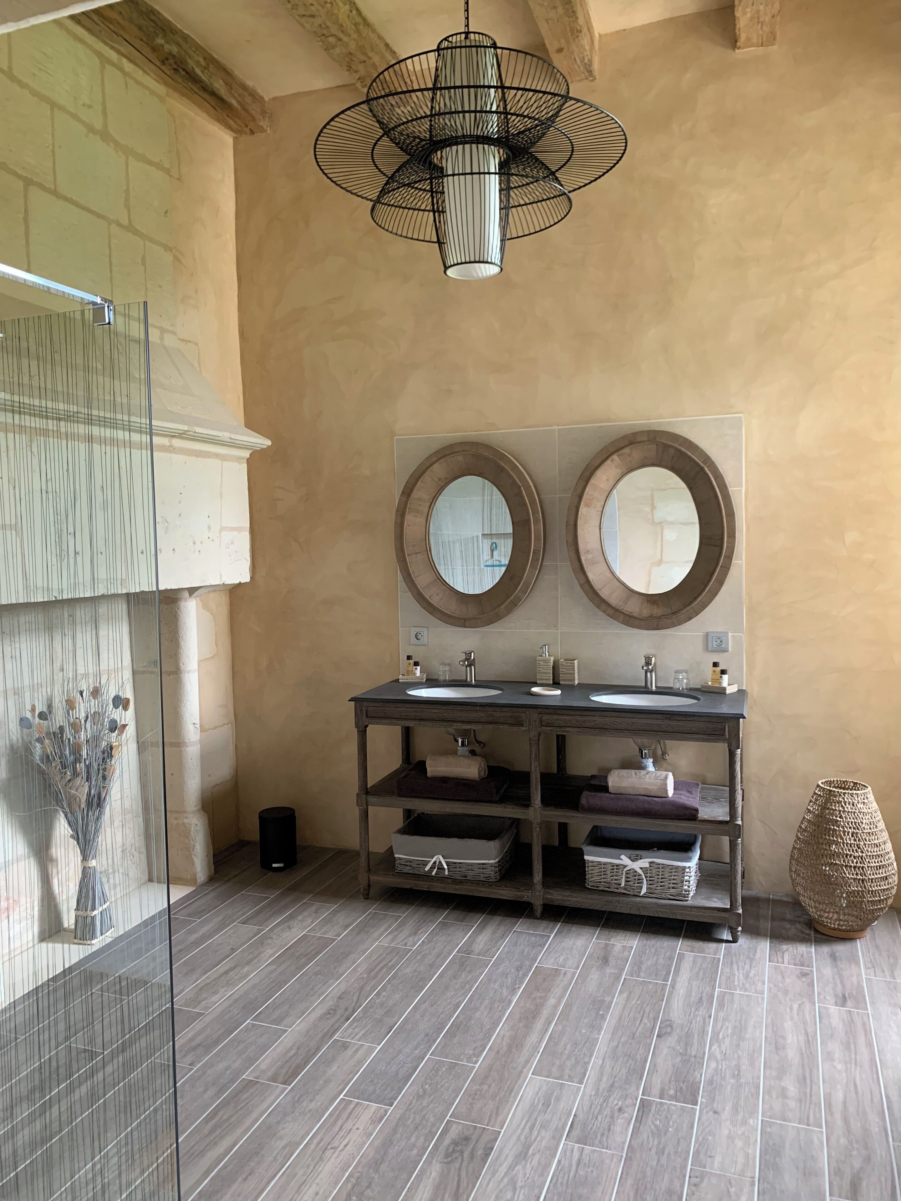 A bathroom with two sinks, a large mirror, and a hanging light fixture.