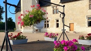 A stone building with a black roof, a turret, and a hanging flower pot. - Les Trois-Moutiers (Les-Trois-Moutiers)