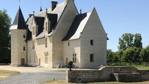A large, historic stone building with multiple towers and steeply pitched roofs, likely a castle or manor house. - Les Trois-Moutiers (Les-Trois-Moutiers)