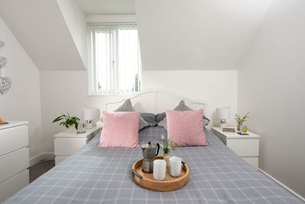 A bedroom with a bed, bedside tables, a window, and a view of the outdoors. - Sunshine Cottage - a cottage that sleeps 4 guests in 2 bedrooms (Padstow)