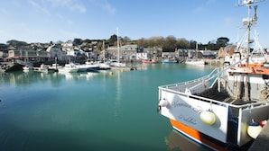 A harbor with boats docked, a building with a sign, and a clear sky. - Sunshine Cottage -  a cottage that sleeps 4 guests  in 2 bedrooms (Padstow)