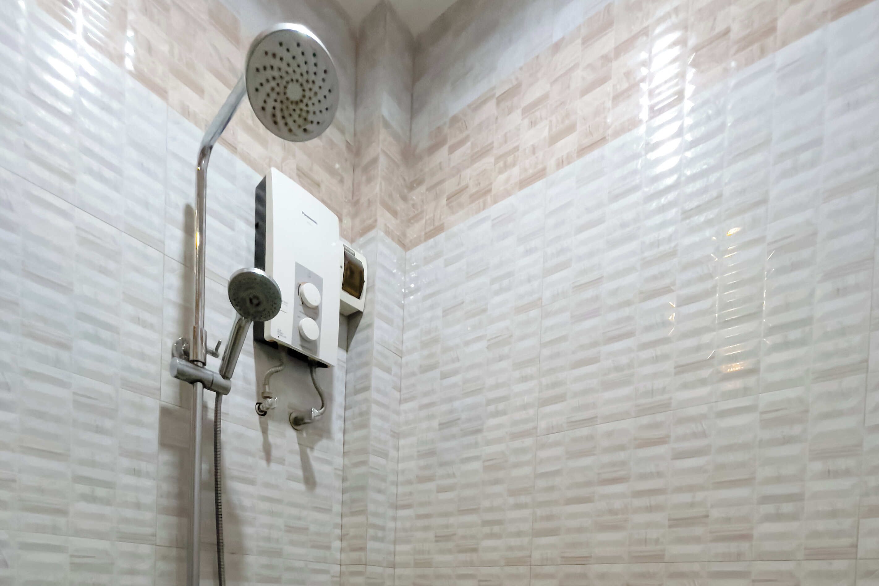 Un baño moderno con ducha, panel de control y toallero de pared.