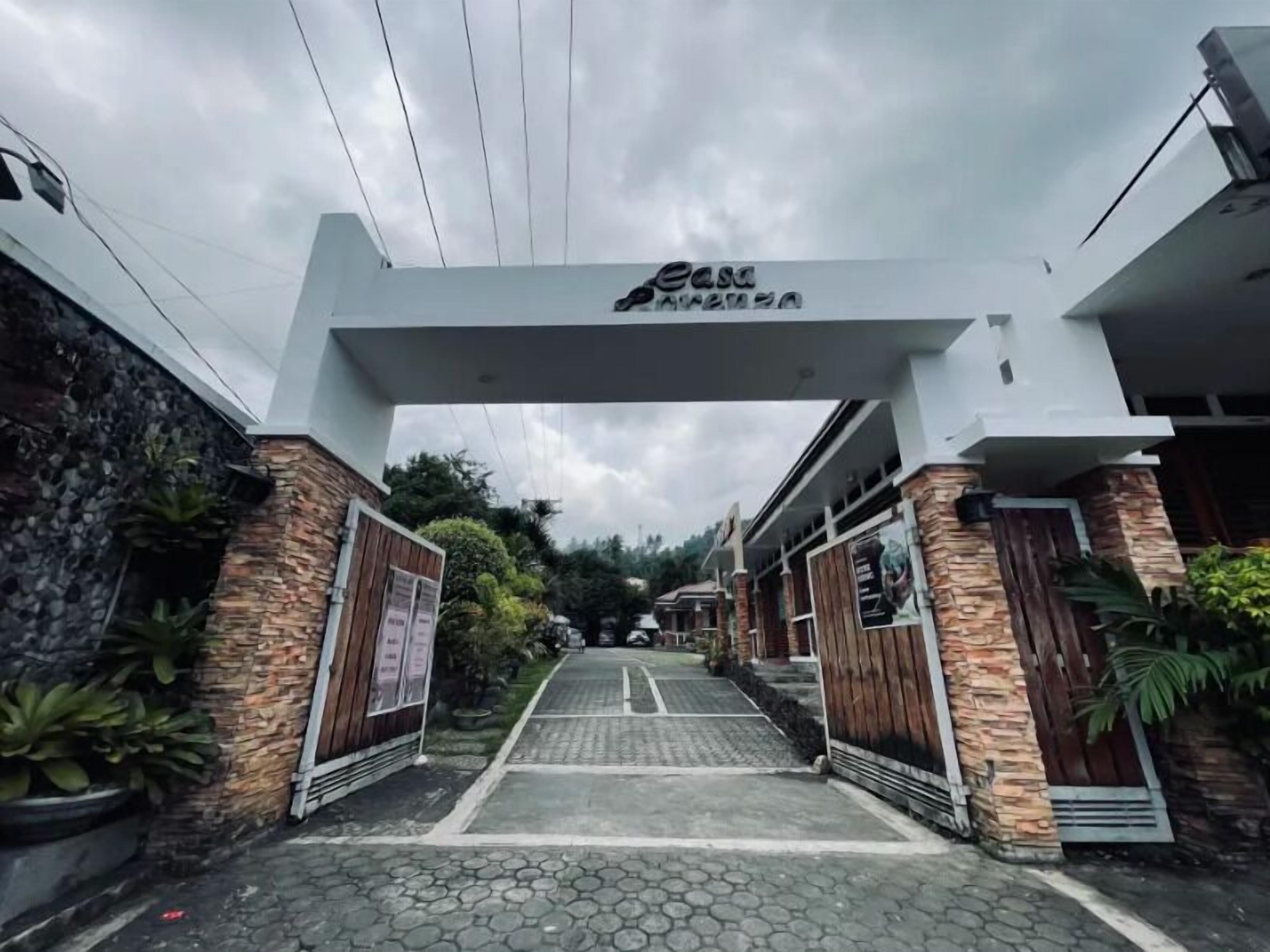Entrada de hotel con fachada de piedra, un letrero sobre la entrada y un camino empedrado que conduce al interior.