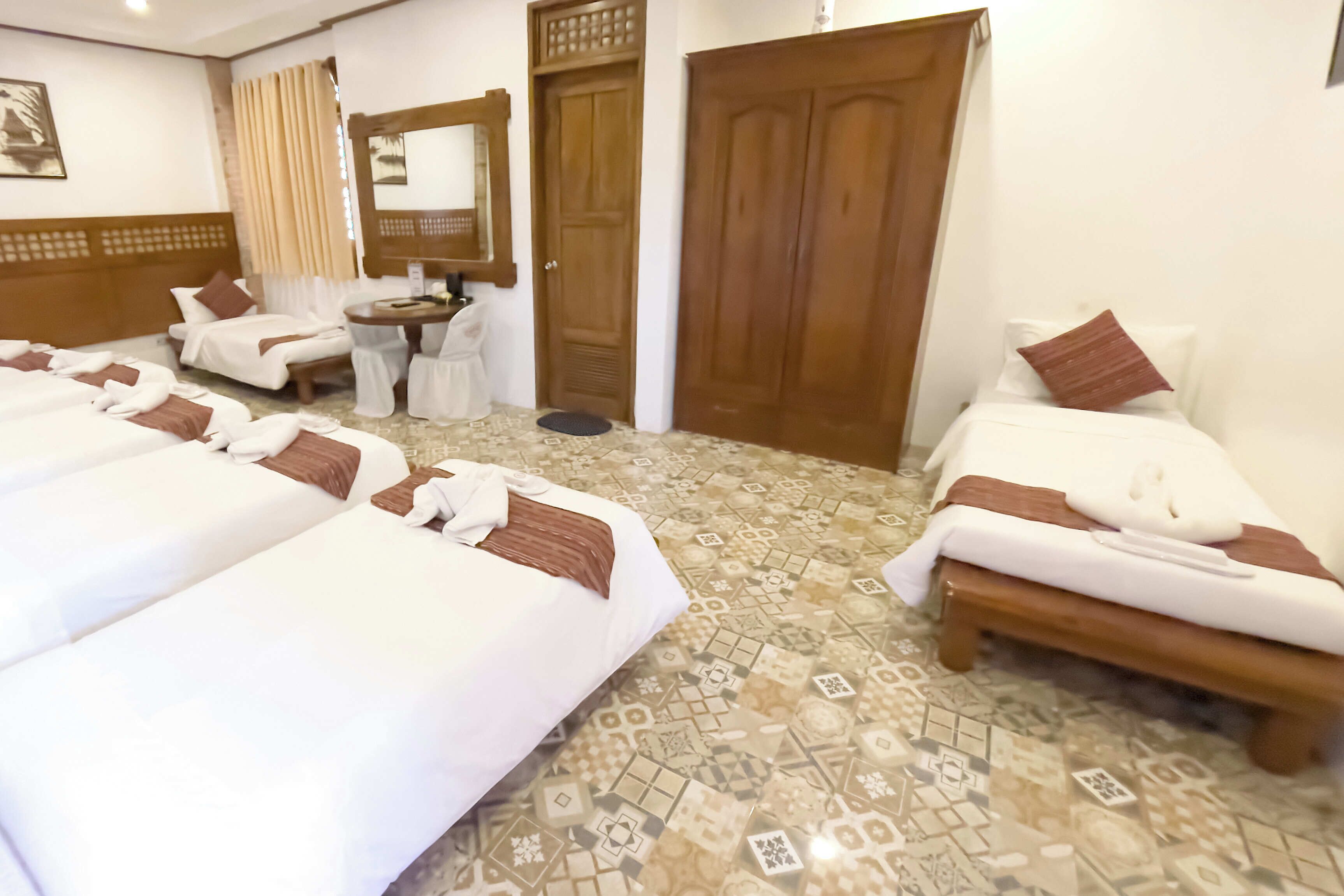 A hotel room with two beds, a desk, a chair, a mirror, and a wardrobe.