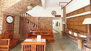A room with a brick wall, wooden staircase, and a wooden bench. - Casa Lorenzo powered by Cocotel (Daraga)