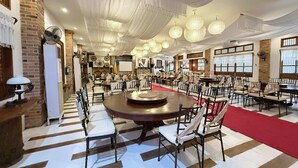 A spacious dining area with multiple tables and chairs, a red carpet, and hanging light fixtures. - Casa Lorenzo powered by Cocotel (Daraga)