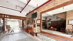 A spacious lobby with a large mirror, a wooden bench, and a stone wall. - Casa Lorenzo powered by Cocotel (Daraga)