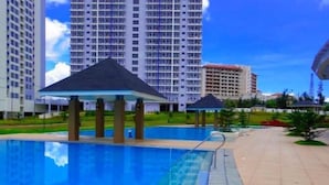 A swimming pool with a pavilion, surrounded by high-rise residential buildings. - Deluxe Family Room in Tagaytay With Taal Lake View (Tagaytay)
