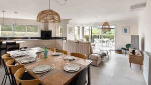 A modern kitchen with a dining area, large windows, and a view of greenery. - Seaside house, all comforts - close to the beaches (Dinard)