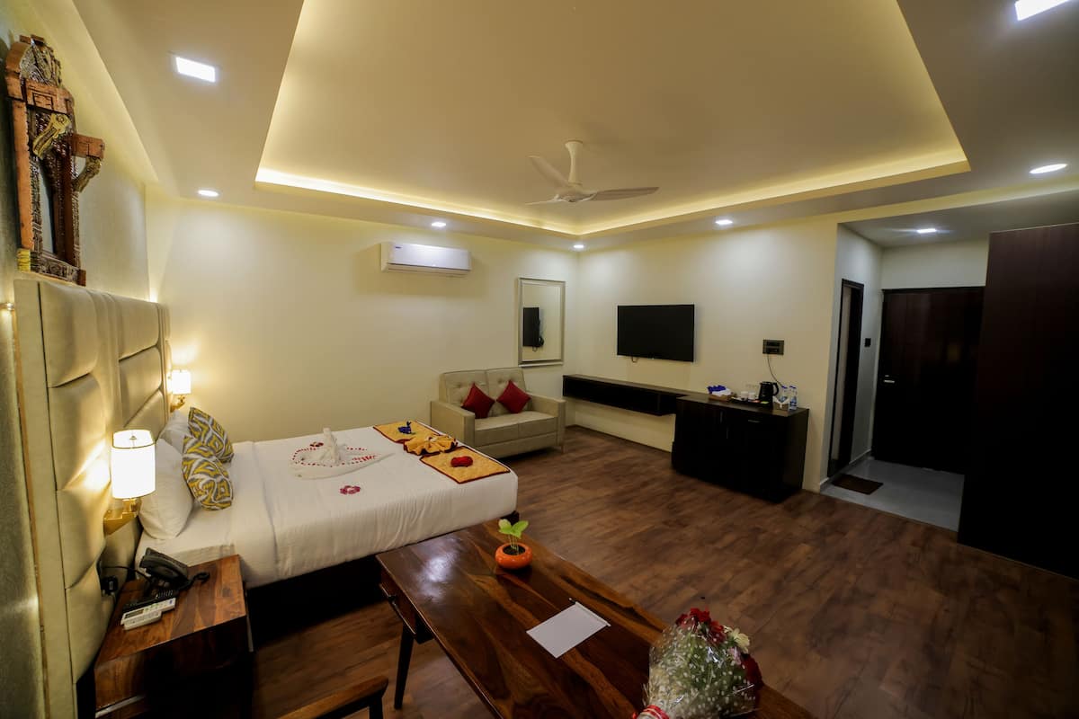 A hotel room with a bed, bedside table, lamp, wooden desk, and a television.