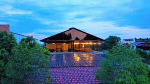 A modern house with a large glass facade, a spacious deck, and a red-tiled roof. - Lake Valley Resort and Spa, Tirupati  (Chinnagottigallu)