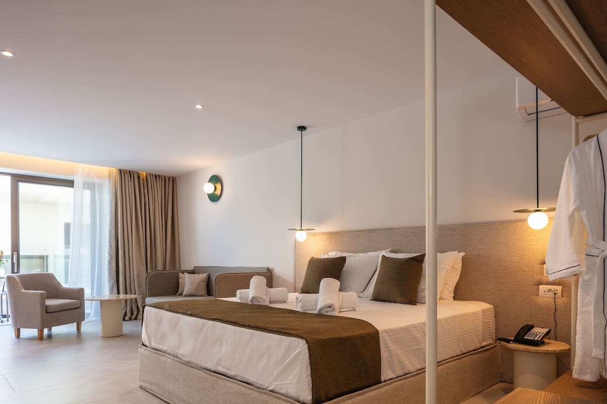 A modern hotel room with a large bed, a bedside table, a chair, and a view of the outdoors.