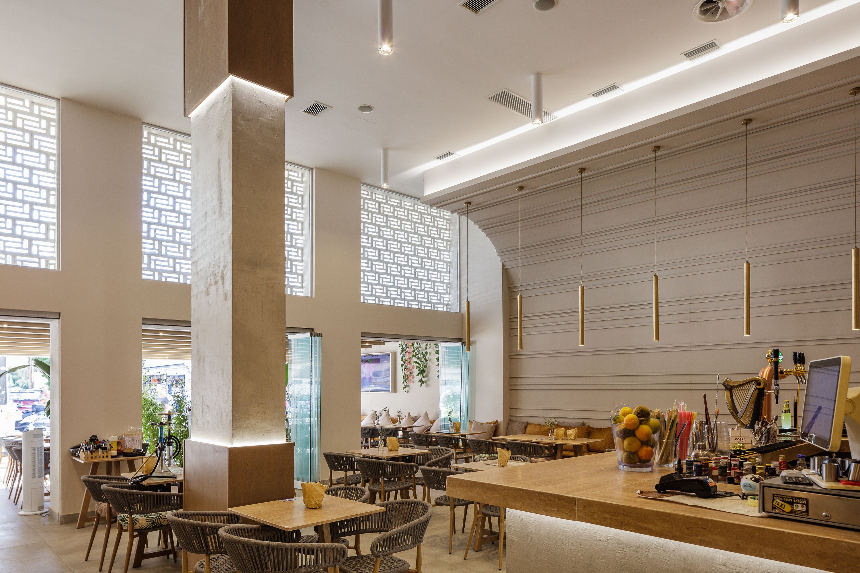 A modern restaurant interior with high ceilings, exposed brick walls, and a mix of wooden and upholstered seating.
