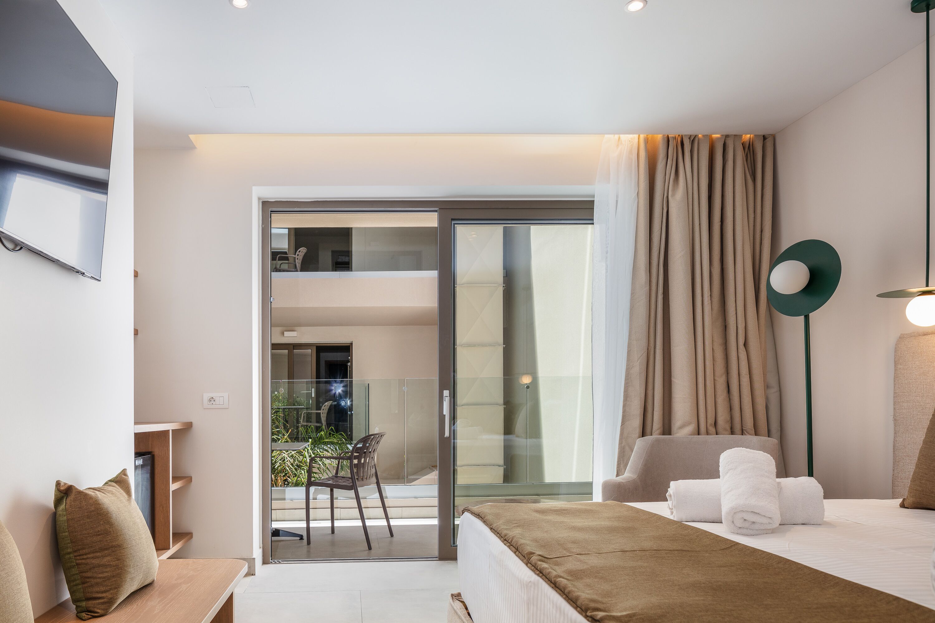 Ein modernes Hotelzimmer mit Bett, einer Sitzecke und einem Balkon mit Glastür.