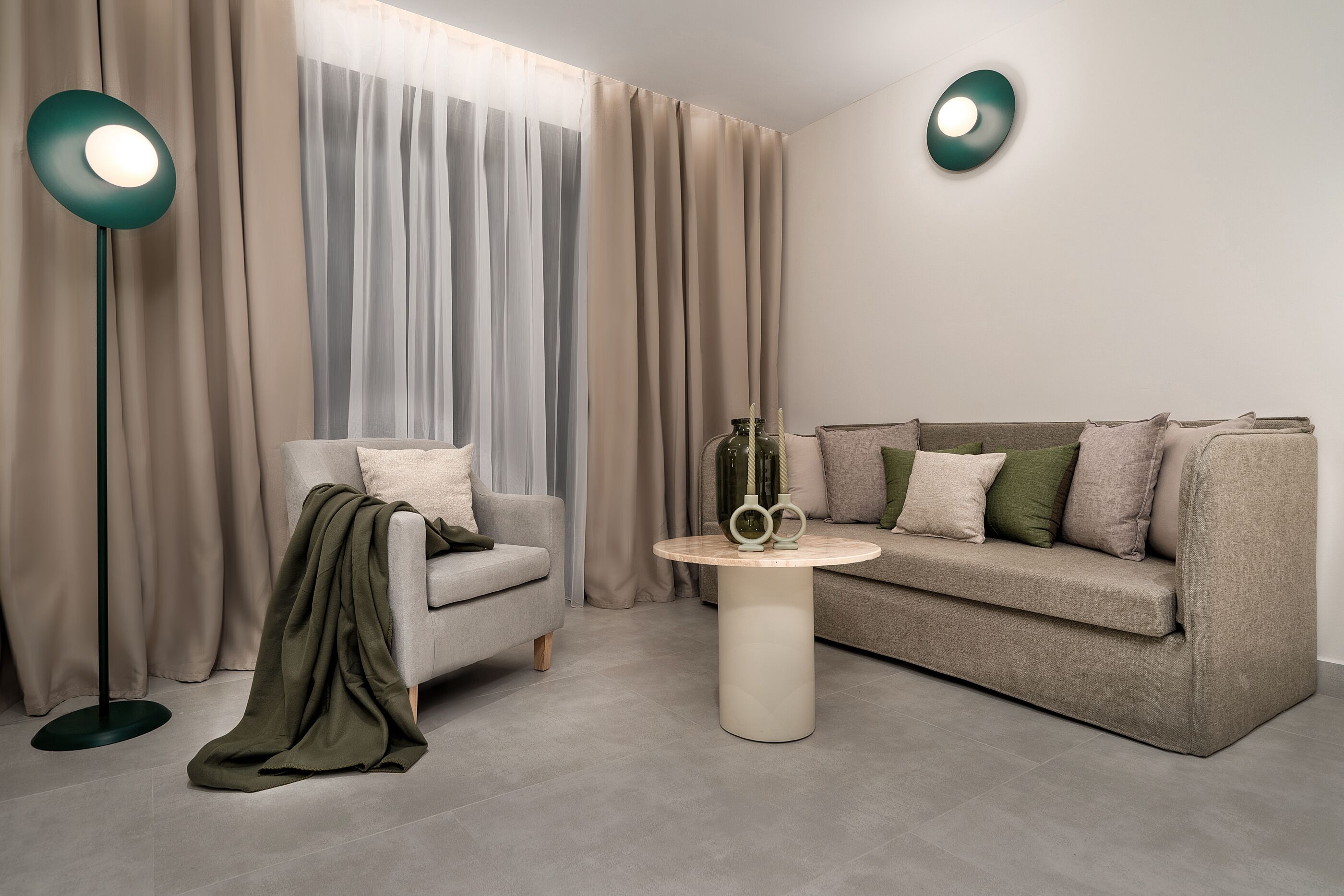 Una sala de estar moderna con un sofá gris, una mesa de centro redonda y una lámpara de pie.