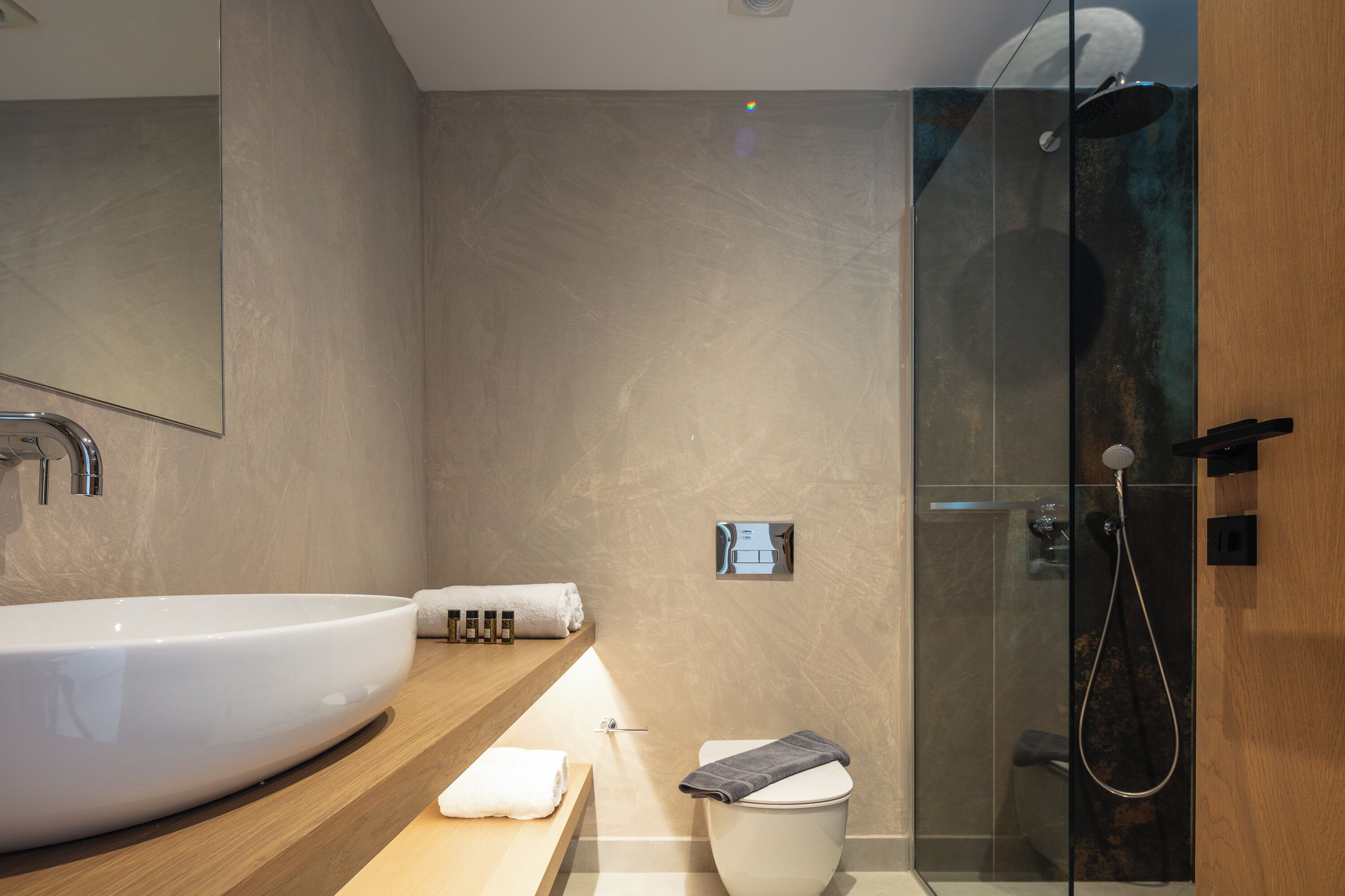 A modern bathroom with a large white sink, a glass-enclosed shower, and a wooden vanity.