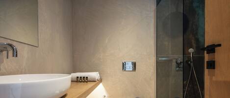 A modern bathroom with a large white sink, a glass-enclosed shower, and a wooden vanity.