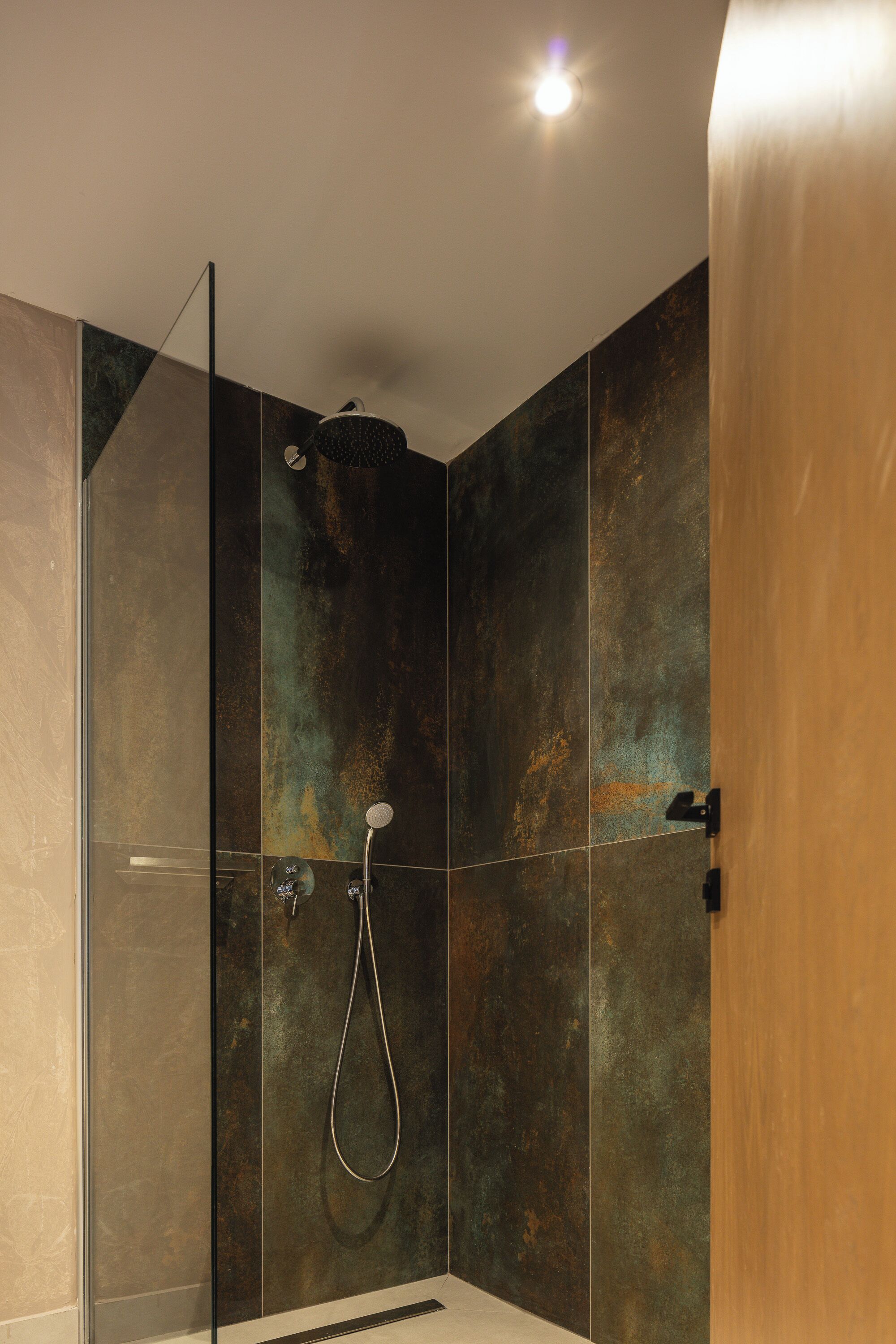 A modern shower with a glass door and a handheld showerhead.