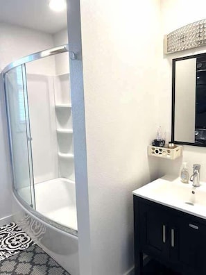 A bathroom with a glass shower enclosure, a white sink, and a mirror above the sink. - A Poolside Paradise (Pensacola)