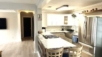 Una cocina moderna con una isla central, electrodomésticos de acero inoxidable y un área de comedor con dos sillas.