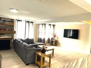A living room with a sofa, wooden coffee table, and a flat-screen TV mounted on the wall. - A Poolside Paradise (Pensacola)