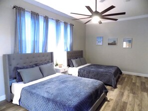 Ein Hotelzimmer mit zwei Betten, einem Deckenventilator und einem Fenster mit Vorhängen.