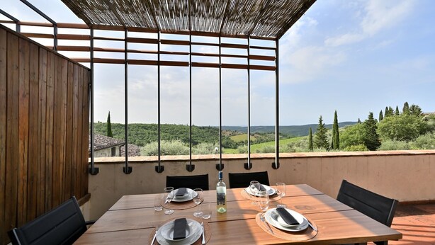 Une table dressée pour deux personnes, avec vue sur un paysage vallonné.