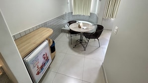 Uma cozinha compacta com área de jantar, com revestimento de azulejos, uma mesa redonda pequena com cadeiras e bancada de madeira.