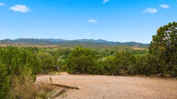 A gravel area with sparse vegetation and distant mountains under a clear sky.