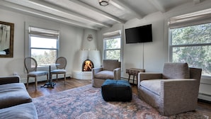 A living room with a fireplace, comfortable seating, and large windows.