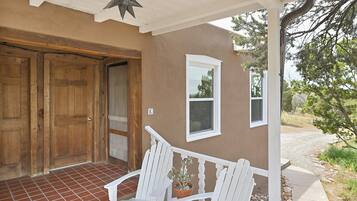 A porch with white wooden chairs, a potted plant, and a star decoration.