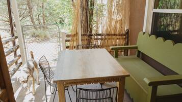 An outdoor patio with a wooden table and metal chairs, surrounded by a bamboo fence.