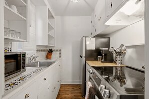 A compact kitchen with white cabinets, a microwave, a sink, and a stove. - Tesuque Outpost |Casita H | Best views in Santa Fe (Santa Fe)