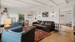 Un salon spacieux avec un canapé en cuir, des fauteuils bleus et un tapis à motifs.