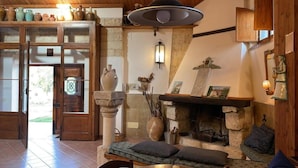 Un interno rustico con camino in pietra, mobili in legno e una varietà di ceramiche sugli scaffali.