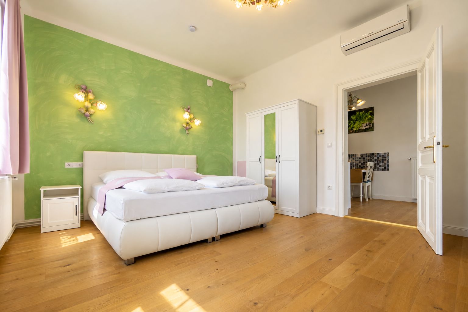 A bedroom with a bed, bedside tables, a wardrobe, and a green accent wall.