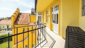 A yellow building with a balcony, a tiled roof, and a white door. - Albizia-Apartments (Baden)