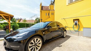 A black electric car charging at a station next to a yellow building. - Albizia-Apartments (Baden)