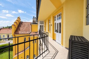 A yellow building with a balcony, a tiled roof, and a window with a white frame.