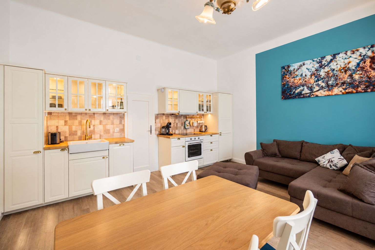 Un espacio habitable compacto con kitchenette, comedor y un conjunto de sofás.