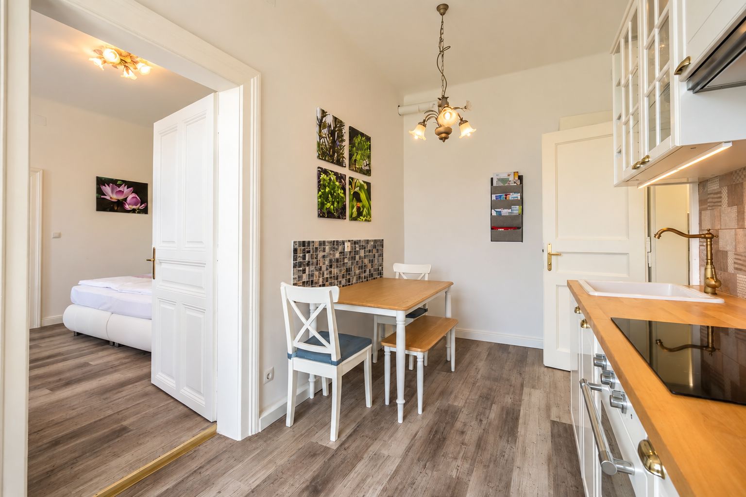 Una cocina moderna con armarios blancos, encimera de madera y un comedor con mesa y sillas blancas.