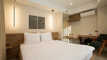 Un dormitorio moderno con una cama grande, un cabecero de madera, un escritorio con una silla y un aire acondicionado de pared.