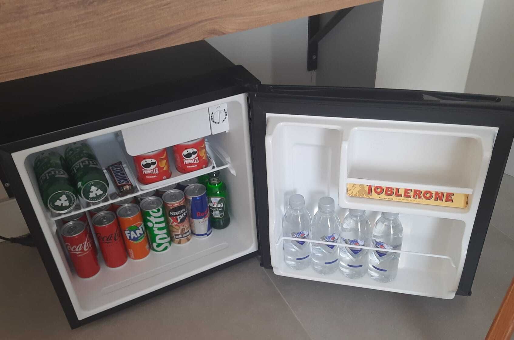 Un mini refrigerador con diferentes bebidas, incluyendo latas y botellas de refresco.