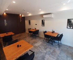 A modern dining area with wooden tables and black chairs, recessed ceiling lighting, and decorative wall art.