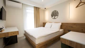 A hotel room with a wooden bed frame, a white desk, a flat-screen TV, and a wall-mounted artwork.