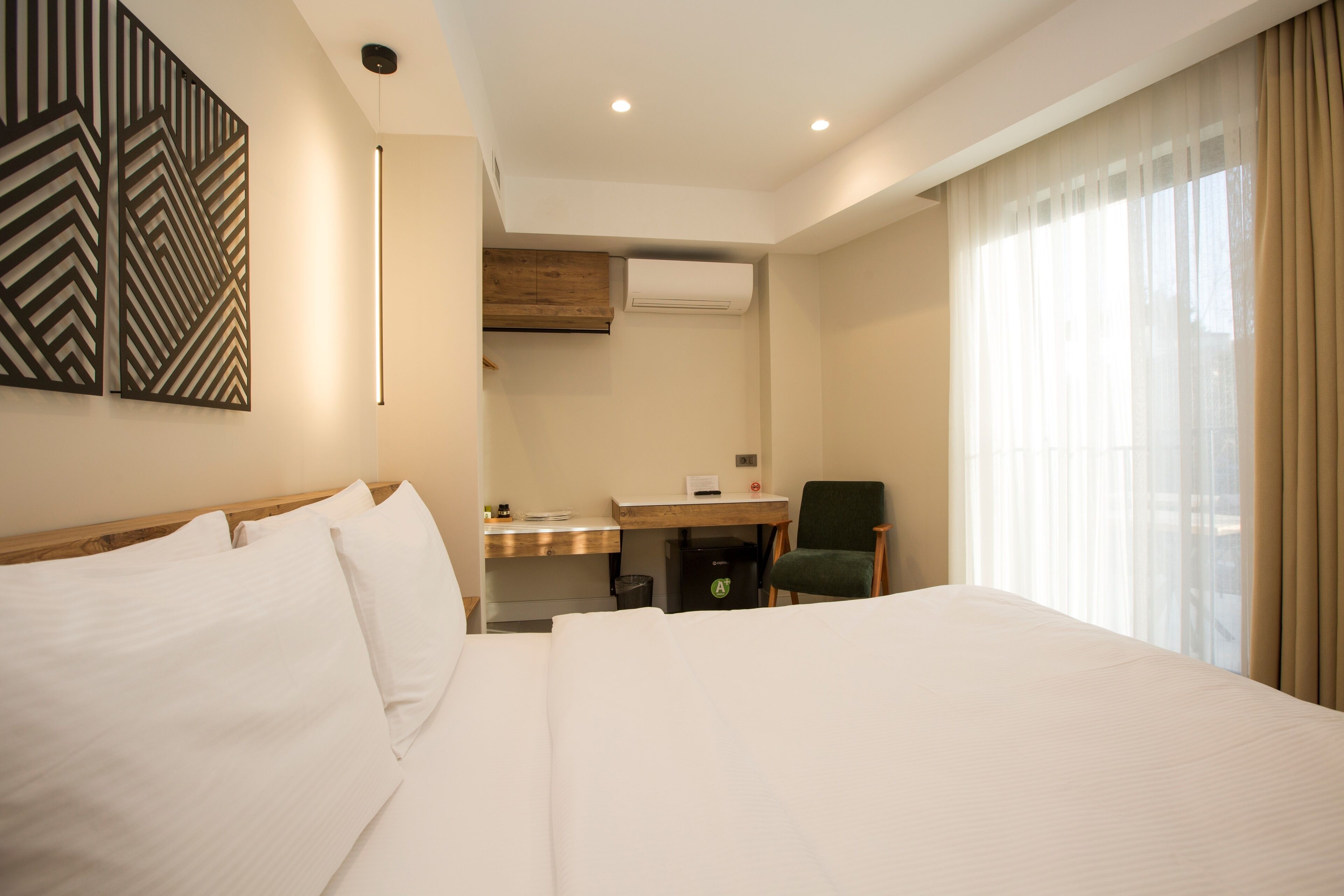 A hotel room with a large bed, a desk, a chair, and a window with curtains.